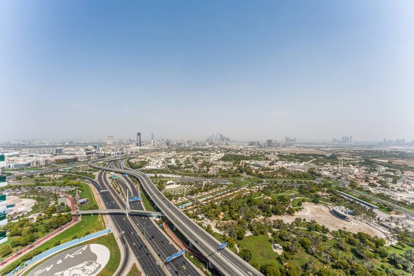 Aerial view of a highway interchange winding through a green urban landscape.
