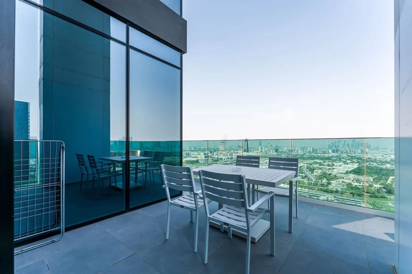 A balcony seating area with a table and chairs beside glass windows.