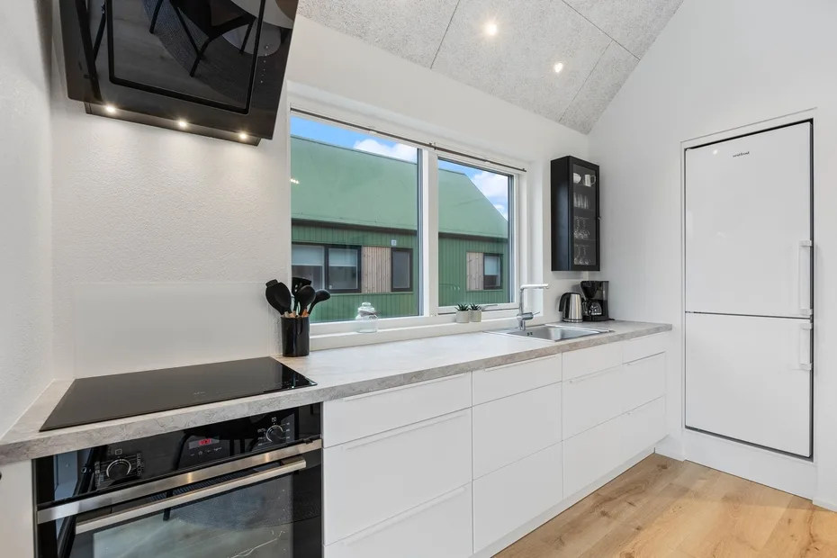 Una cocina luminosa con gabinetes blancos, una encimera y grandes ventanas.