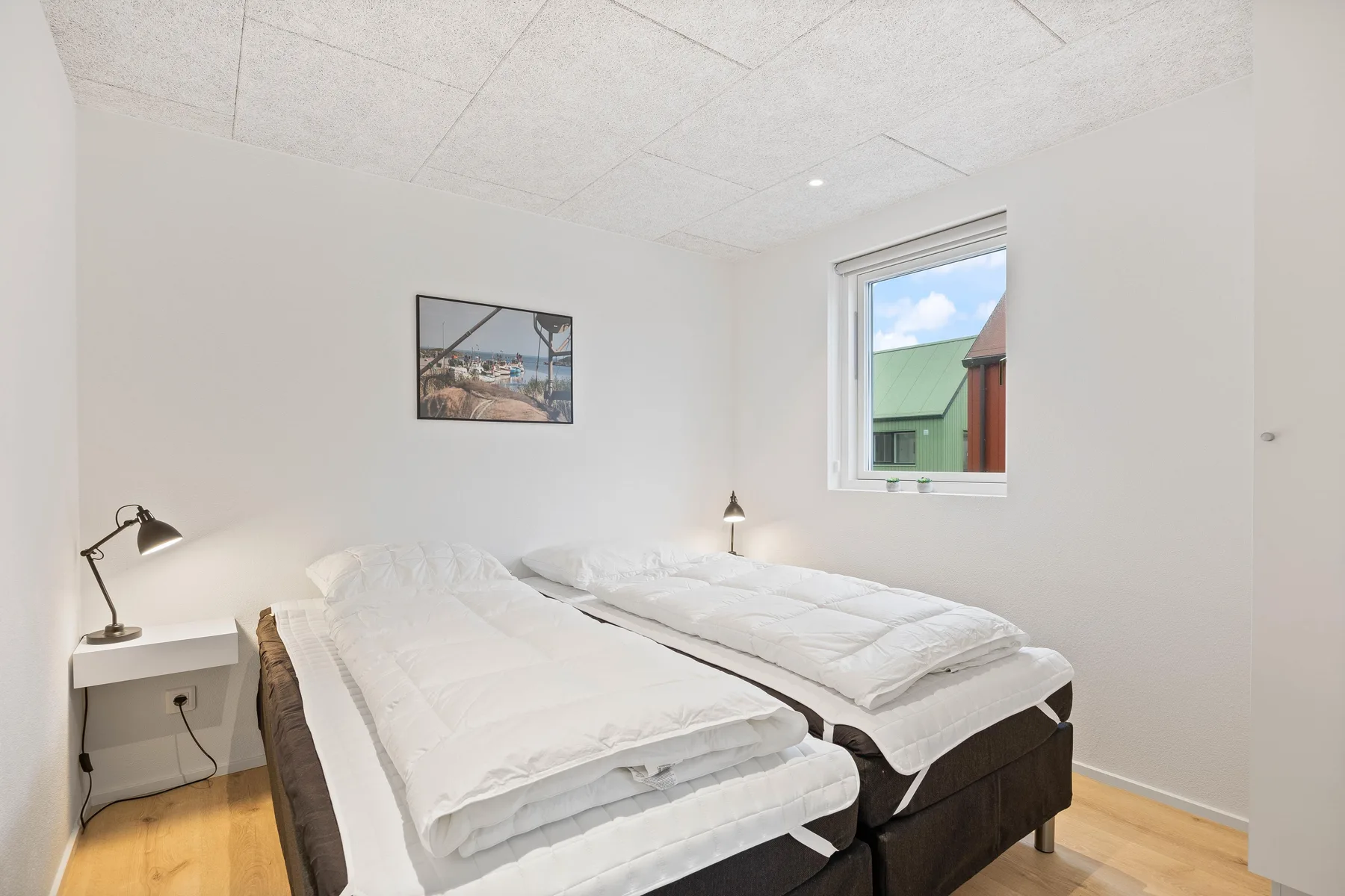 Dormitorio con dos camas junto a una ventana.