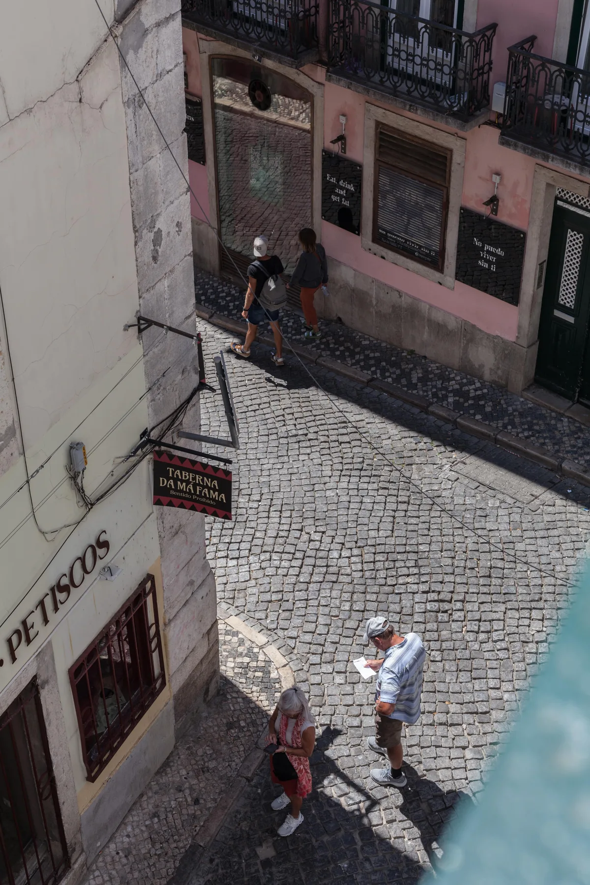 A cobblestone street passes colorful building facades and a small shop.