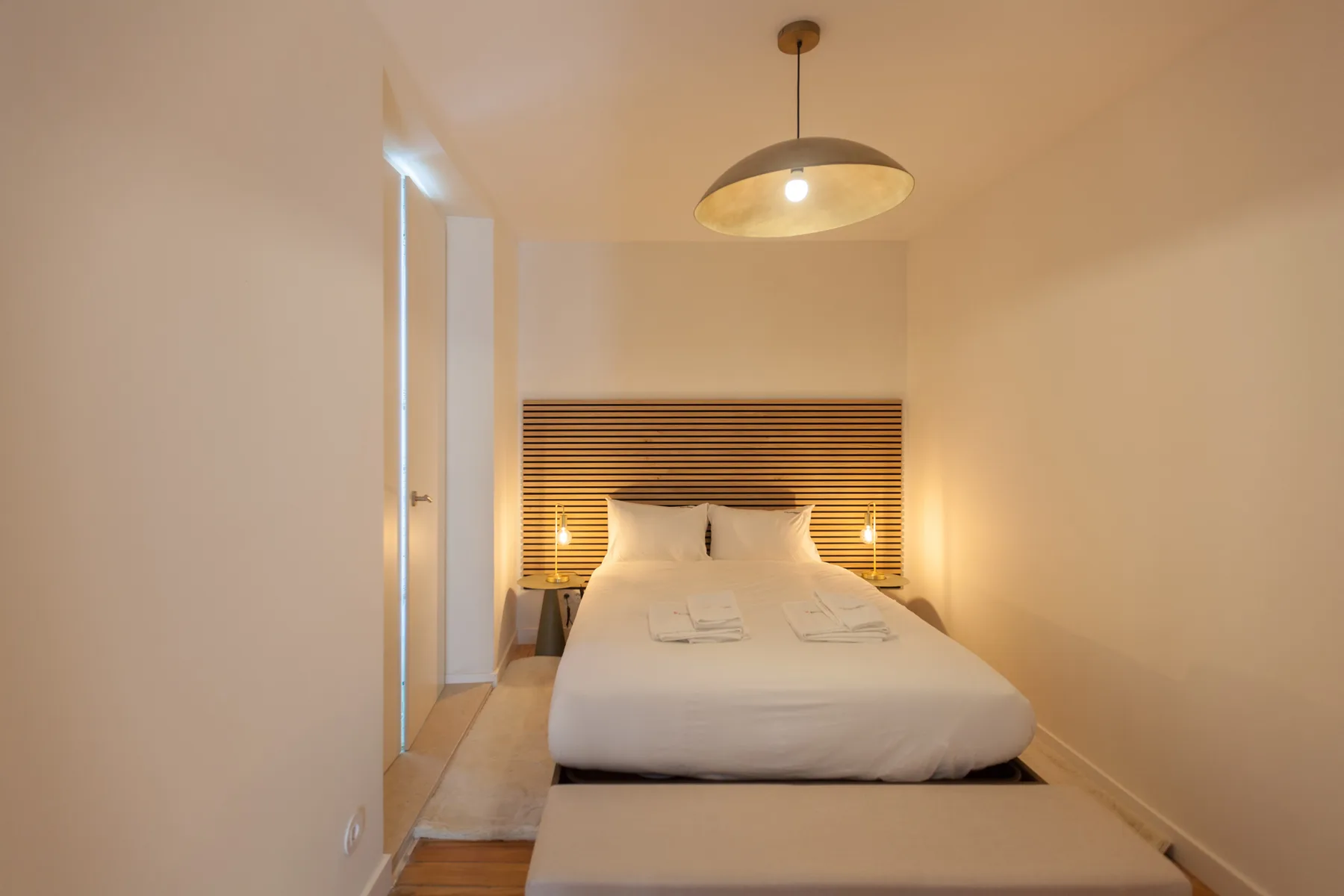 A bedroom with a neatly made bed beneath a striped headboard.