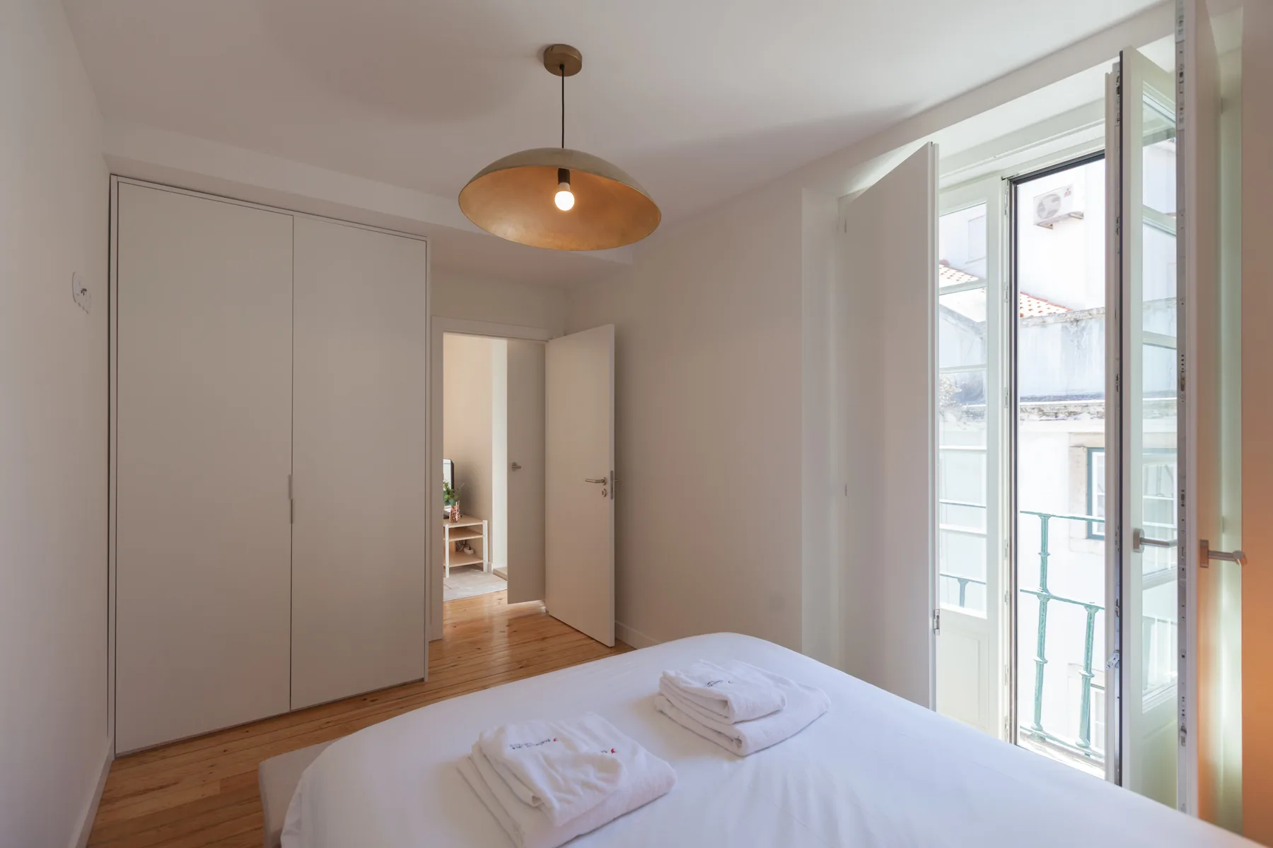 A bedroom with a bed, built-in wardrobes, and tall windows.