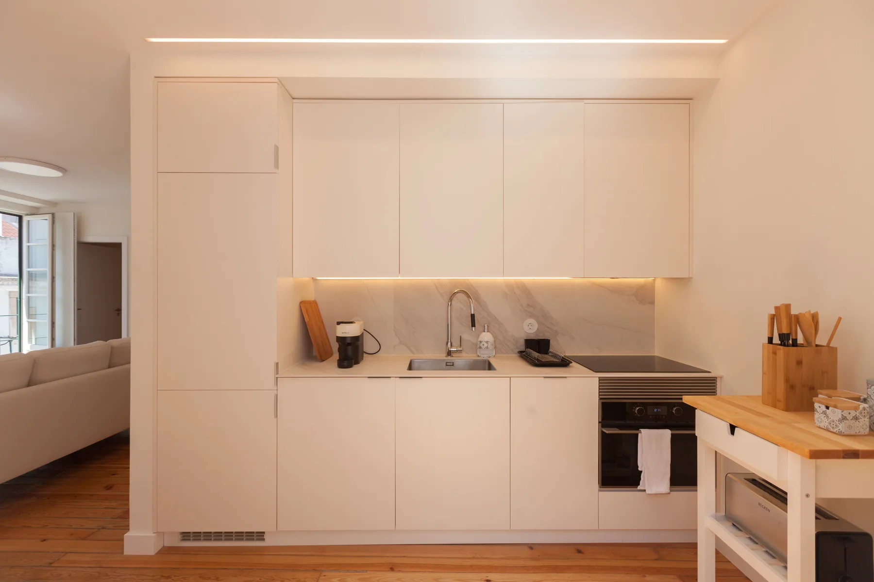 A compact kitchen with pale cabinets and a wooden worktable.