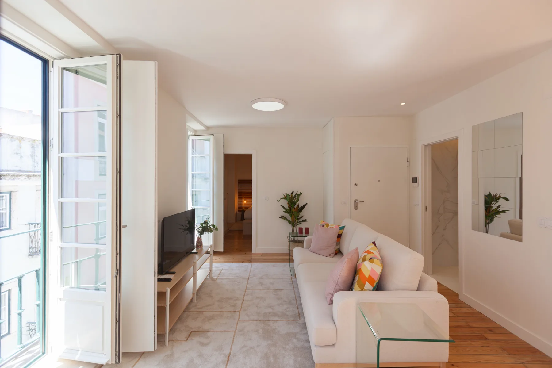 A bright living room with seating beside tall open windows.