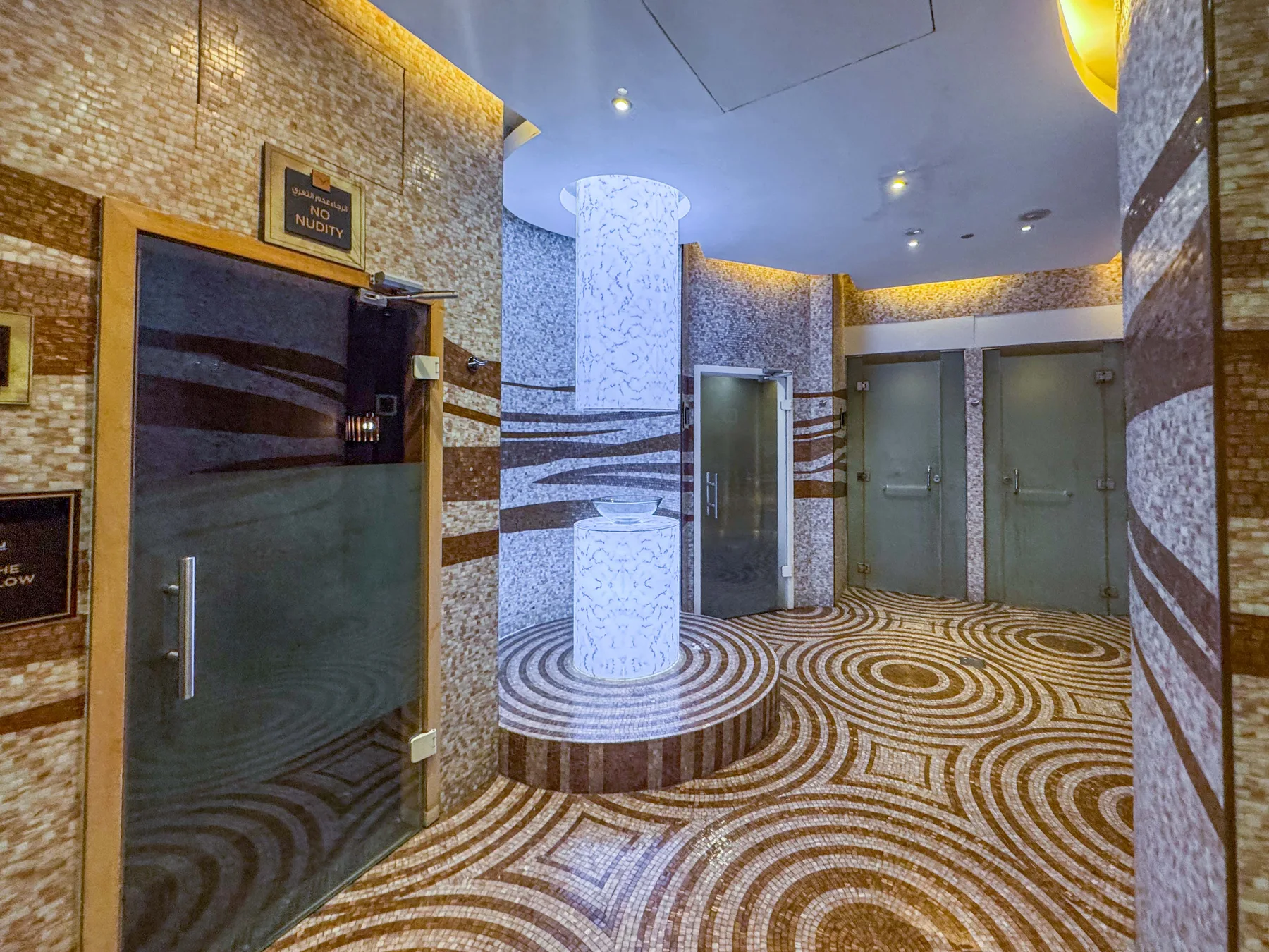 Un vestíbulo interior revestido de azulejos tiene un piso estampado y varias puertas.