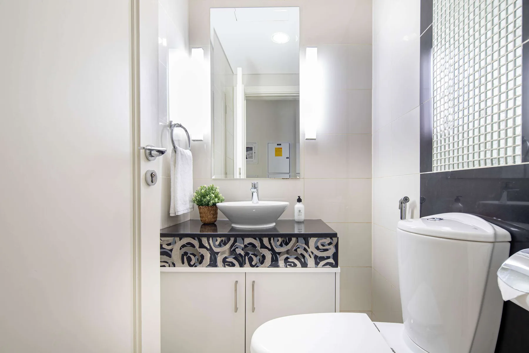 Un baño luminoso con lavabo, espejo e inodoro.