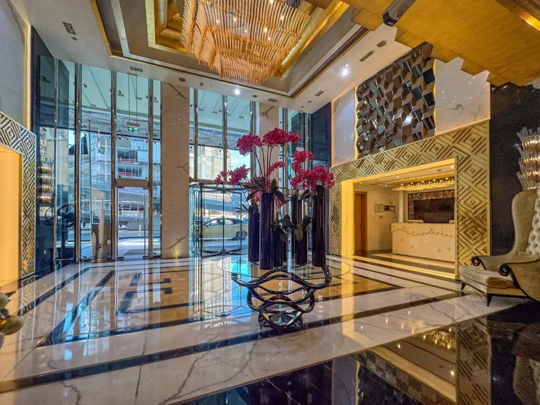 Un amplio vestíbulo de hotel con puertas de vidrio y mostrador de recepción.