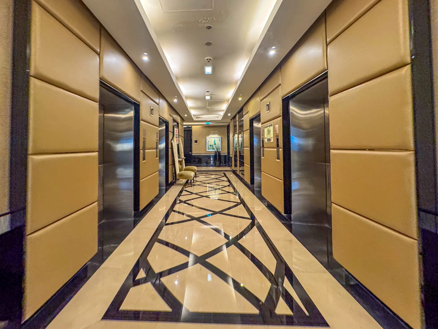 Un pasillo de hotel con ascensores y un suelo de diseño geométrico.