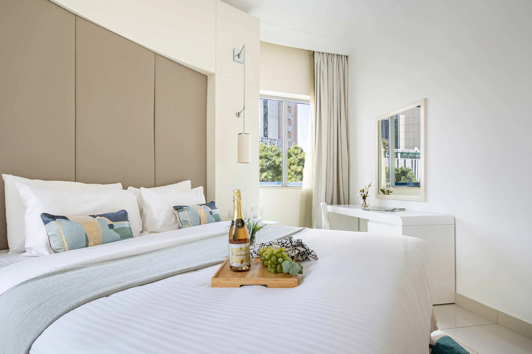 Un dormitorio luminoso con una cama bien tendida y un escritorio junto a la ventana.