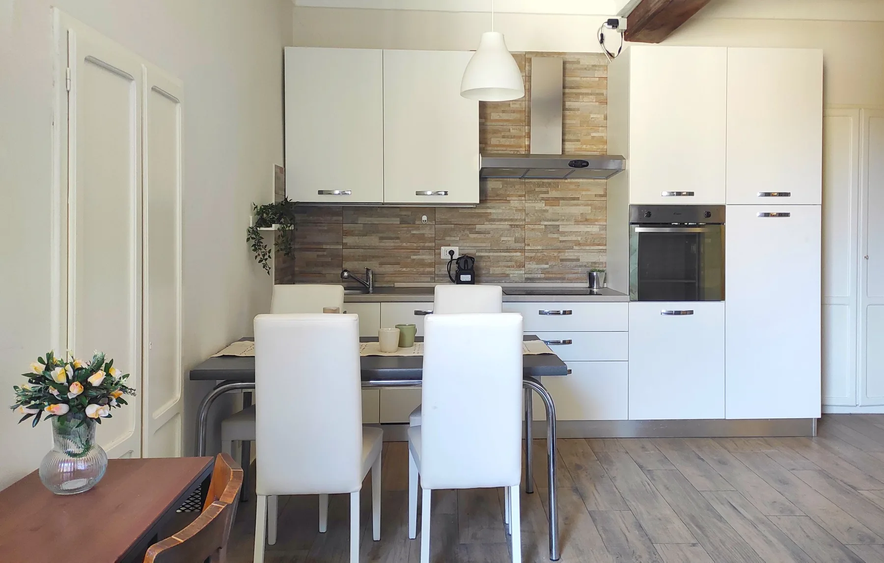 Cocina y comedor modernos con armarios blancos y una mesa.