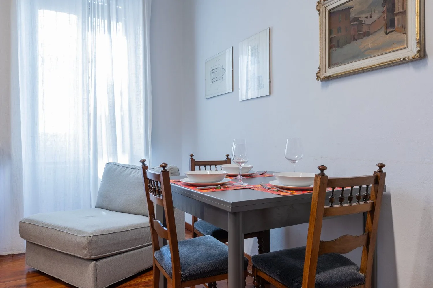 Dining area with a set table beside a window and seating.