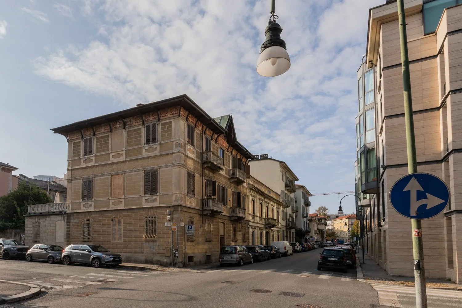 An urban street corner lined with older buildings and parked cars.