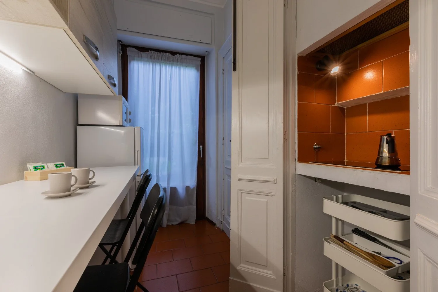 A compact kitchen with a white counter and open shelving.