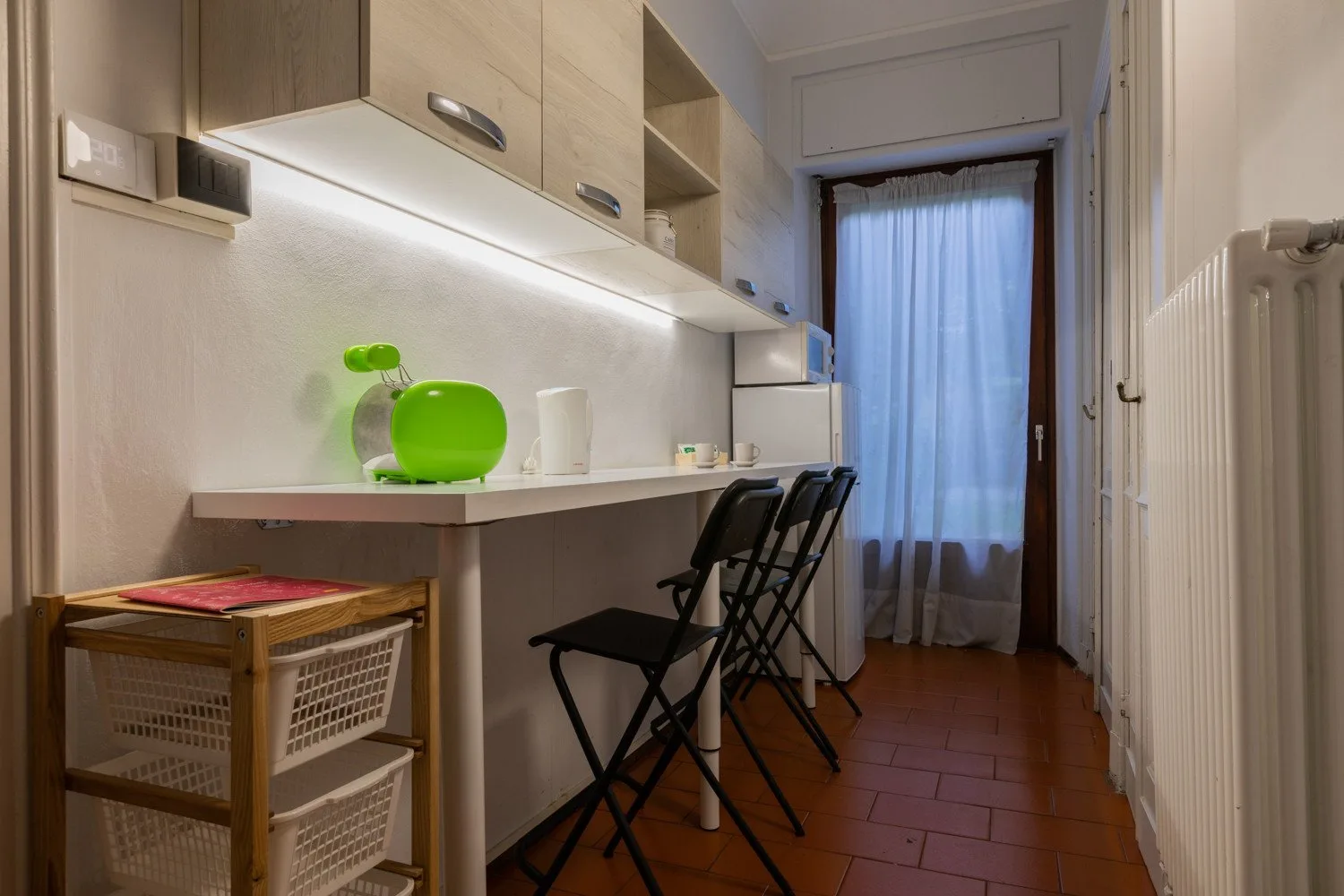 A narrow kitchenette with a counter, cabinets, and folding chairs.