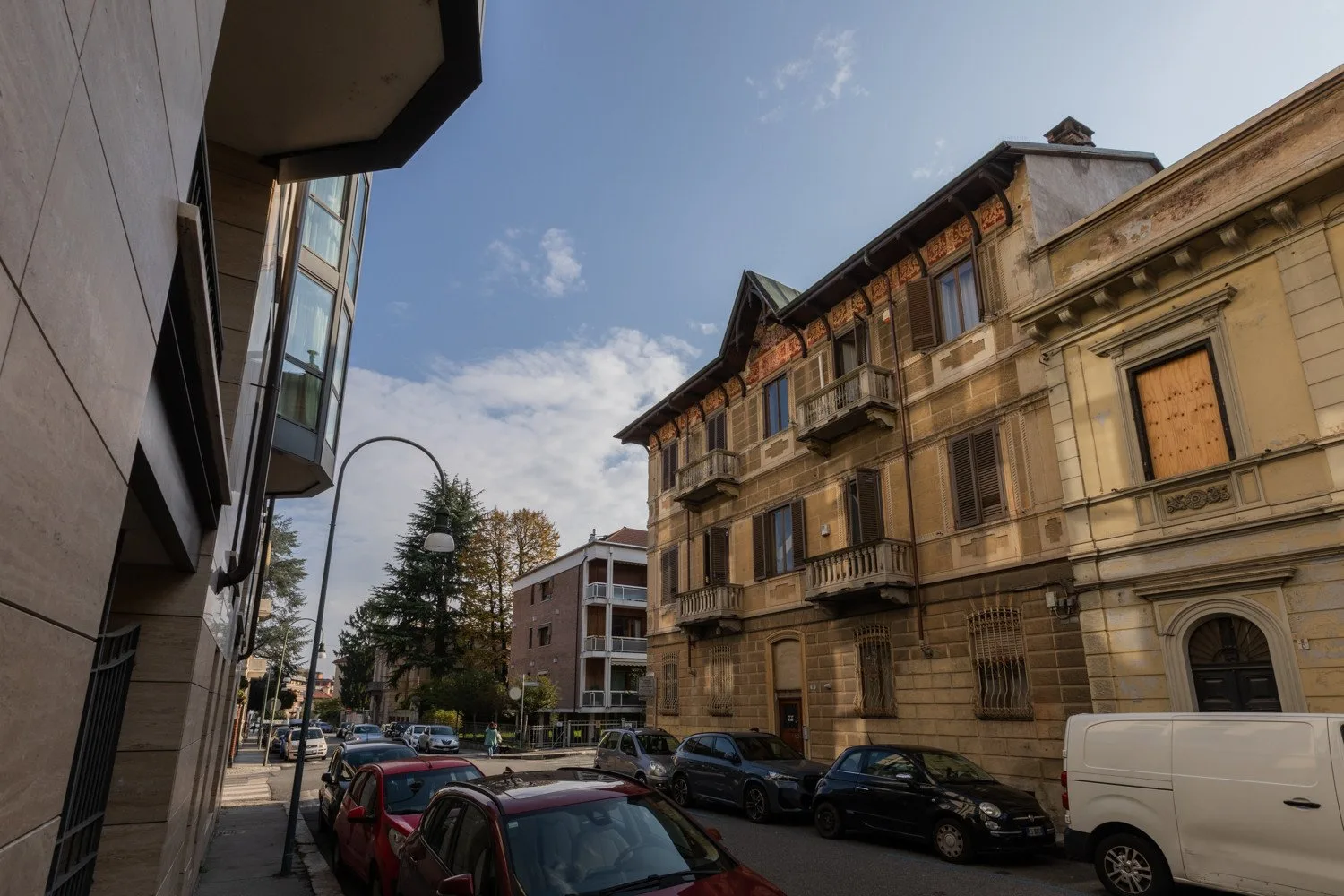 An urban street lined with older buildings and parked cars.