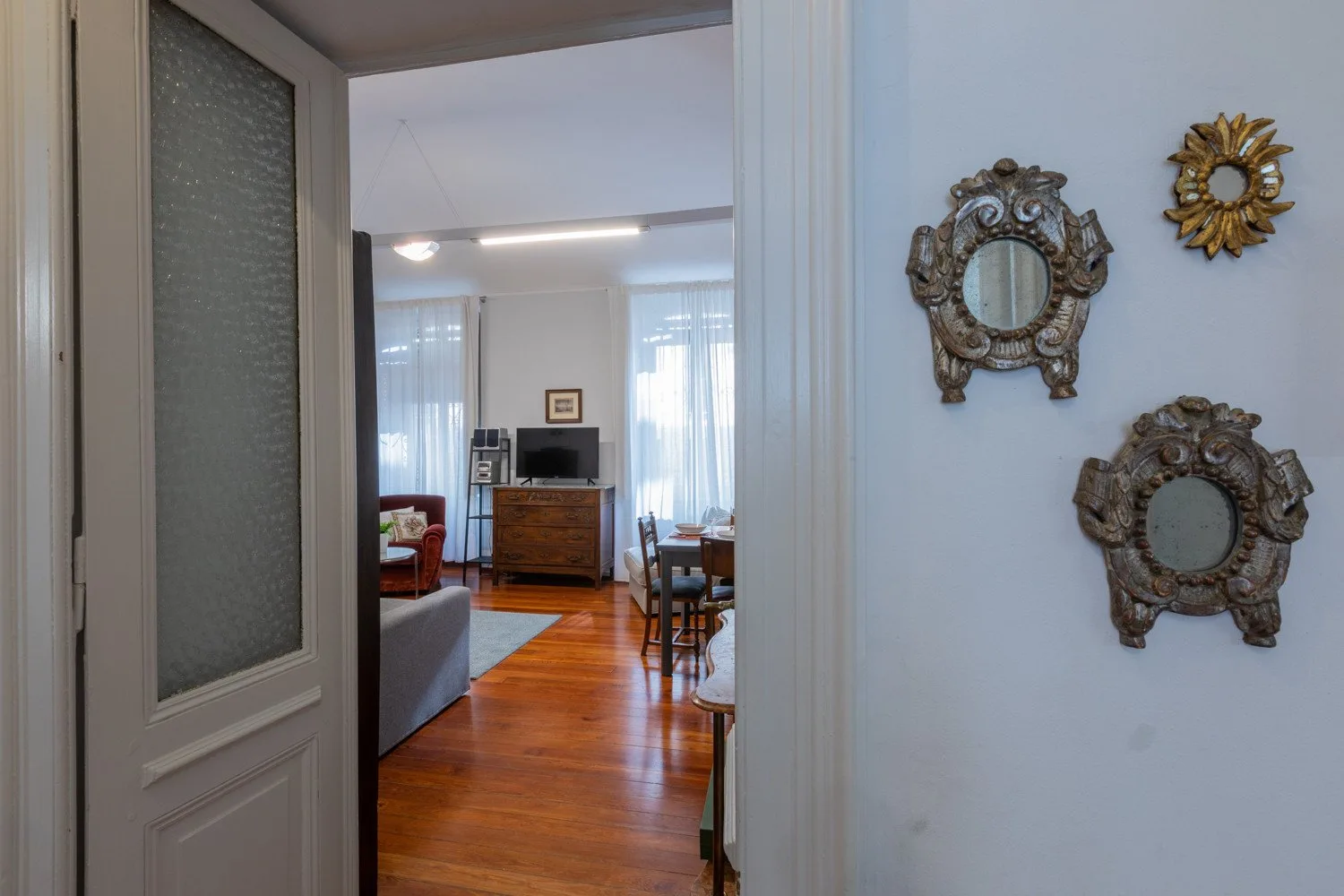 A doorway opens onto a living and dining area with wooden floors.