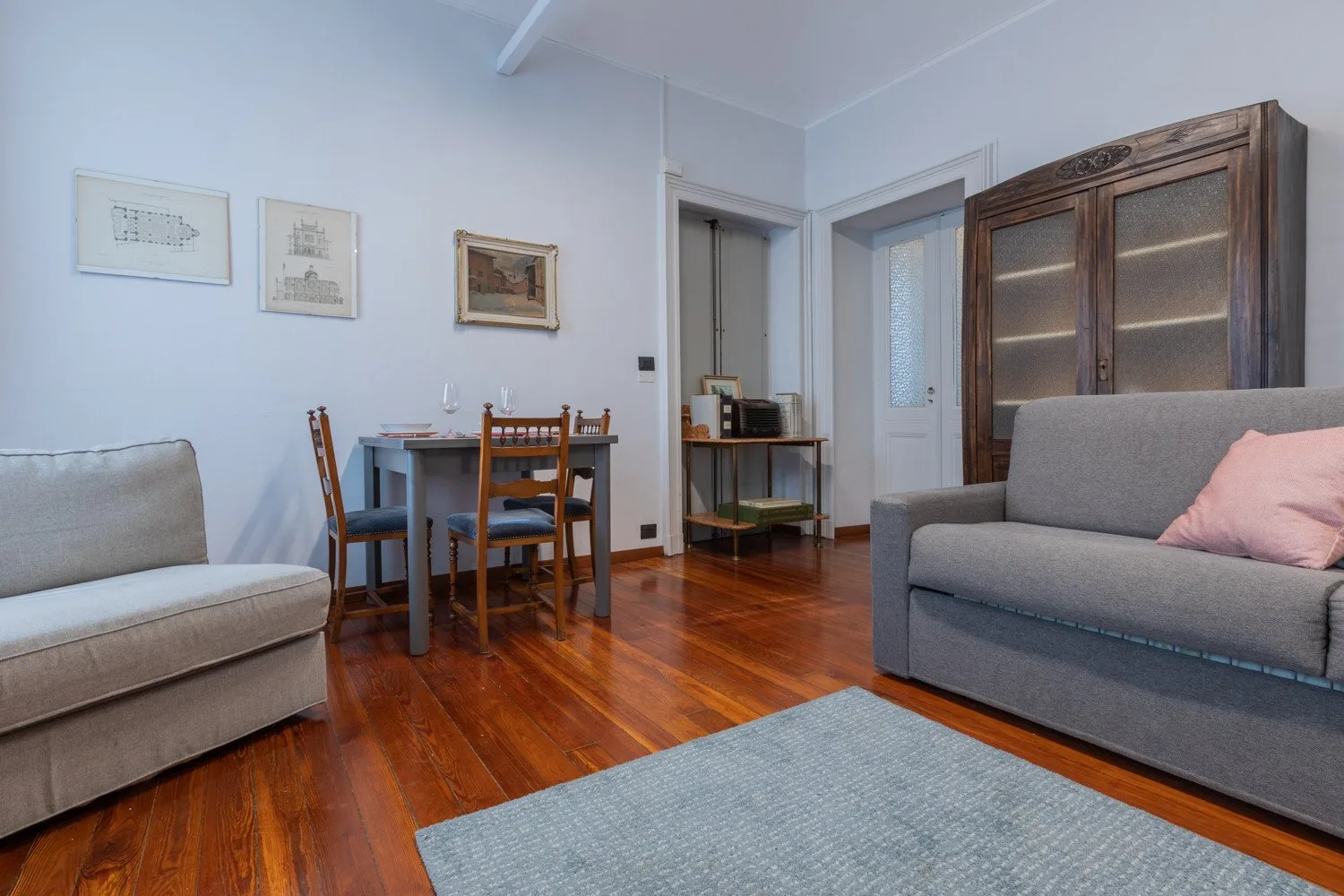 A living room with seating, a dining table, and a wooden floor.