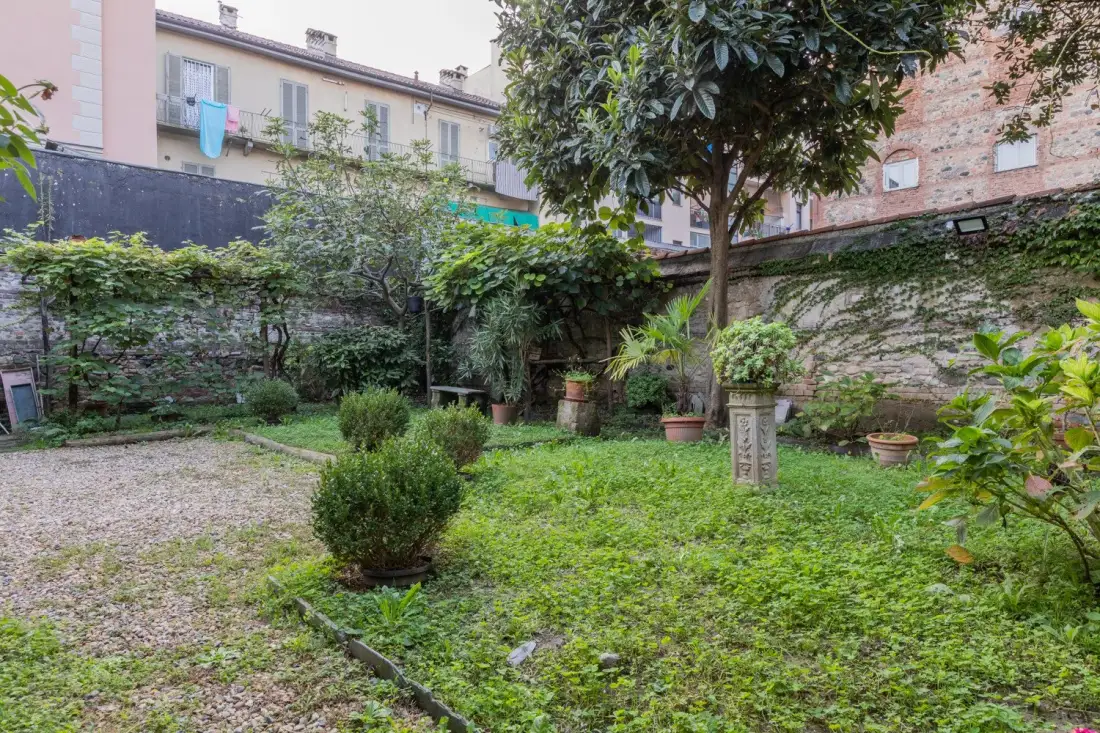 A leafy garden courtyard with potted plants and a gravel path.