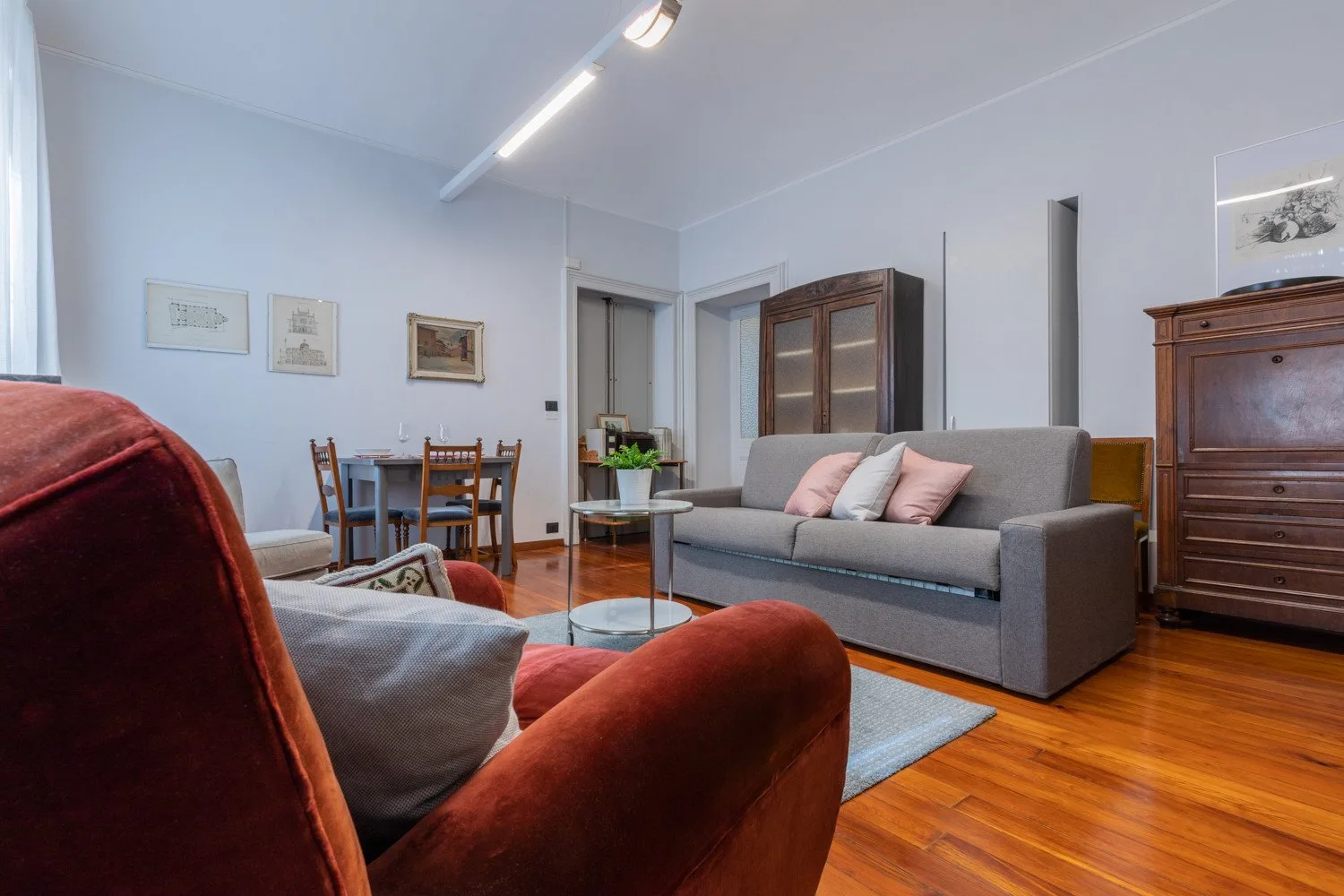 A living room with a gray sofa, armchairs, and a dining table.