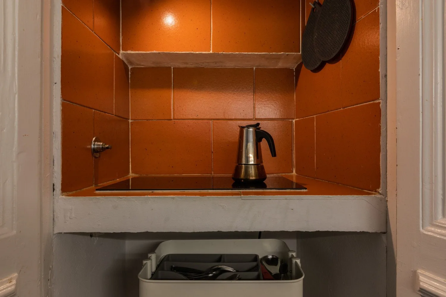 A tiled kitchenette alcove with an electric kettle on the counter.