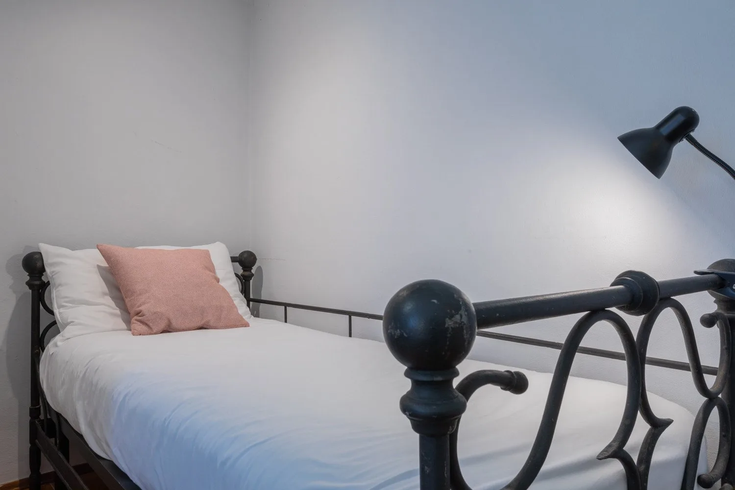 A bedroom with a bed, white bedding, and a black metal frame.