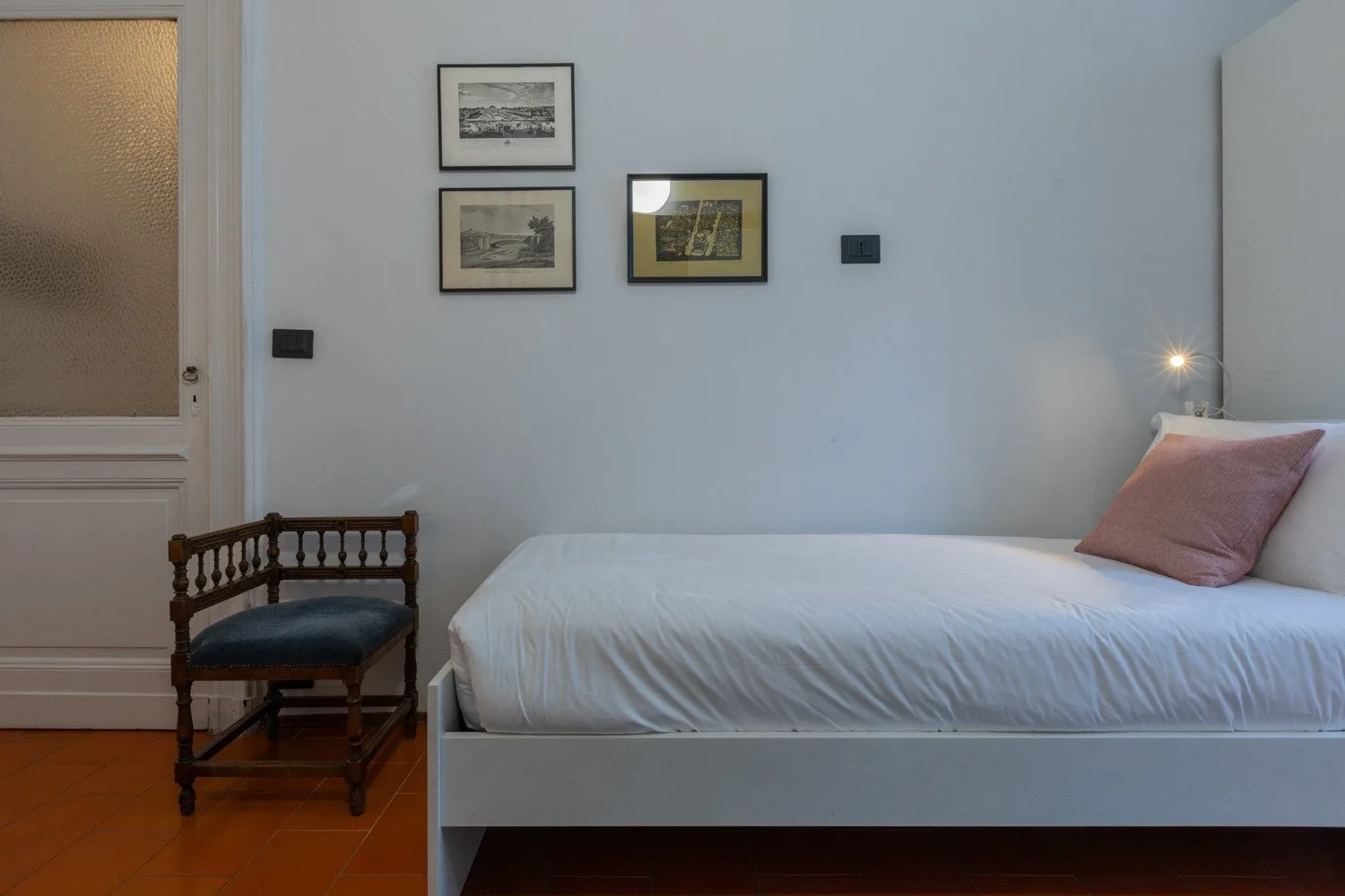 A bedroom with a neatly made bed and framed pictures on the wall.