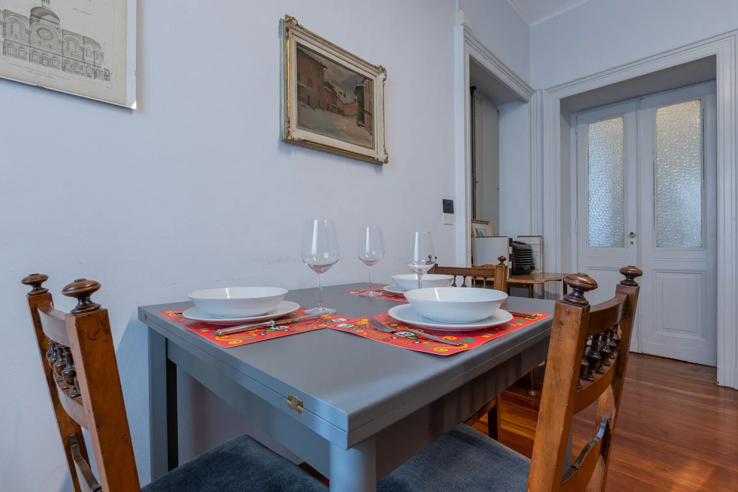 Dining area with a set table, wooden seating, and a frosted-glass door.