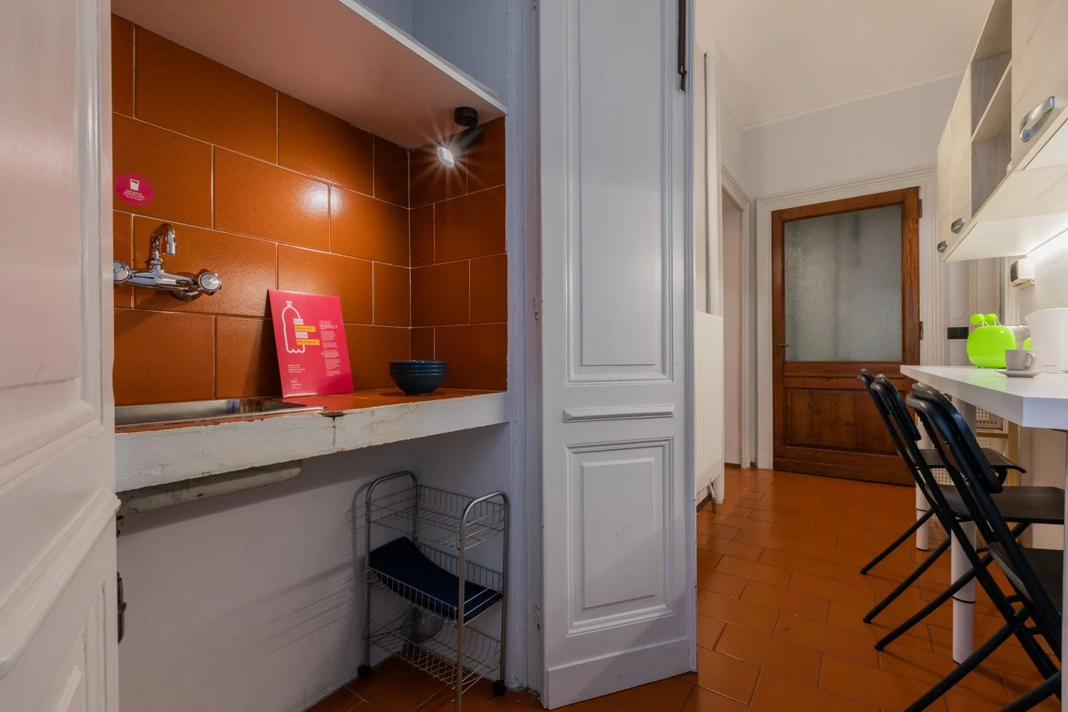 A tiled kitchen area with a counter, sink, and dining table.