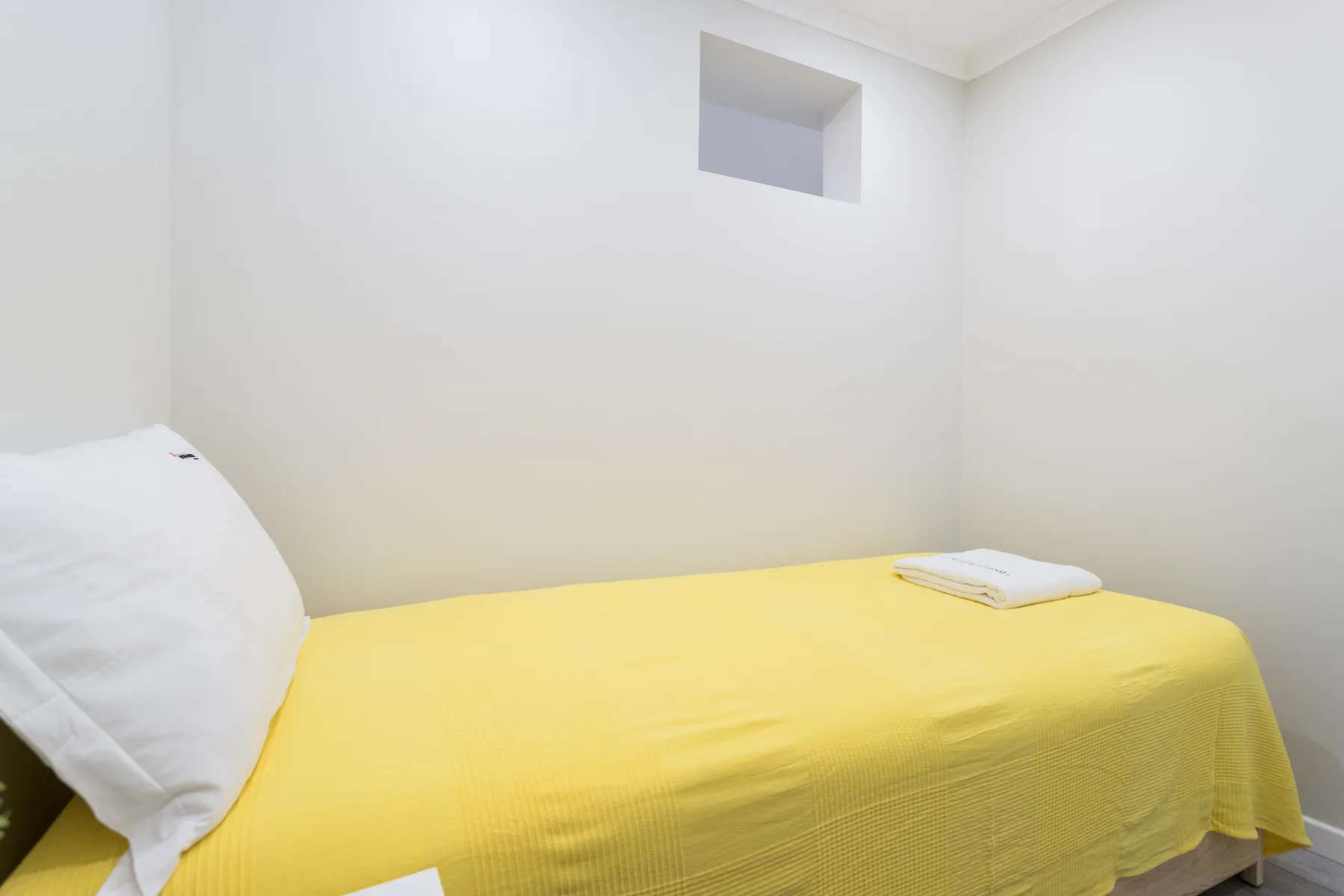 A bedroom with a bed covered in a yellow bedspread.
