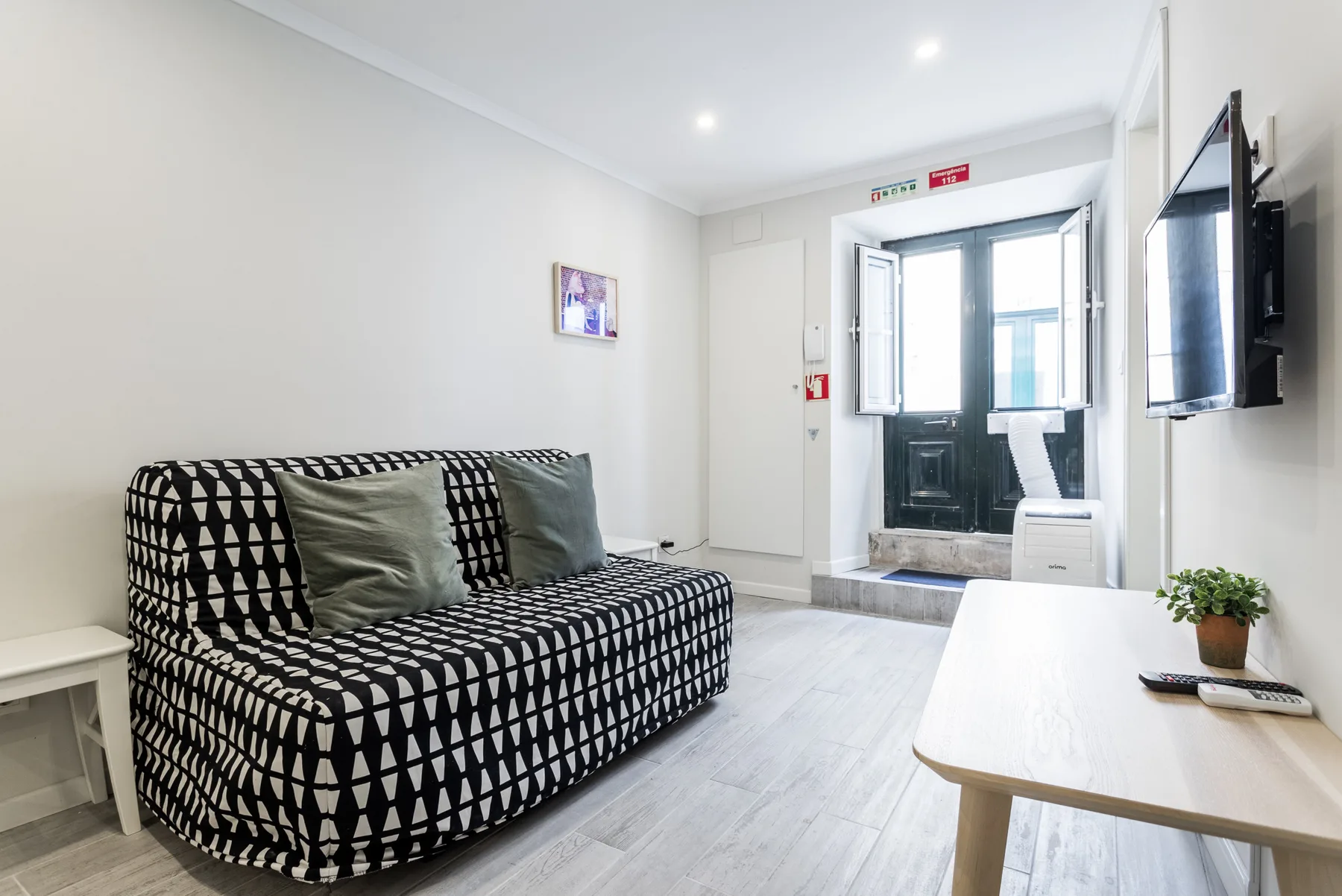 A bright living room with patterned seating, a coffee table, and a television.