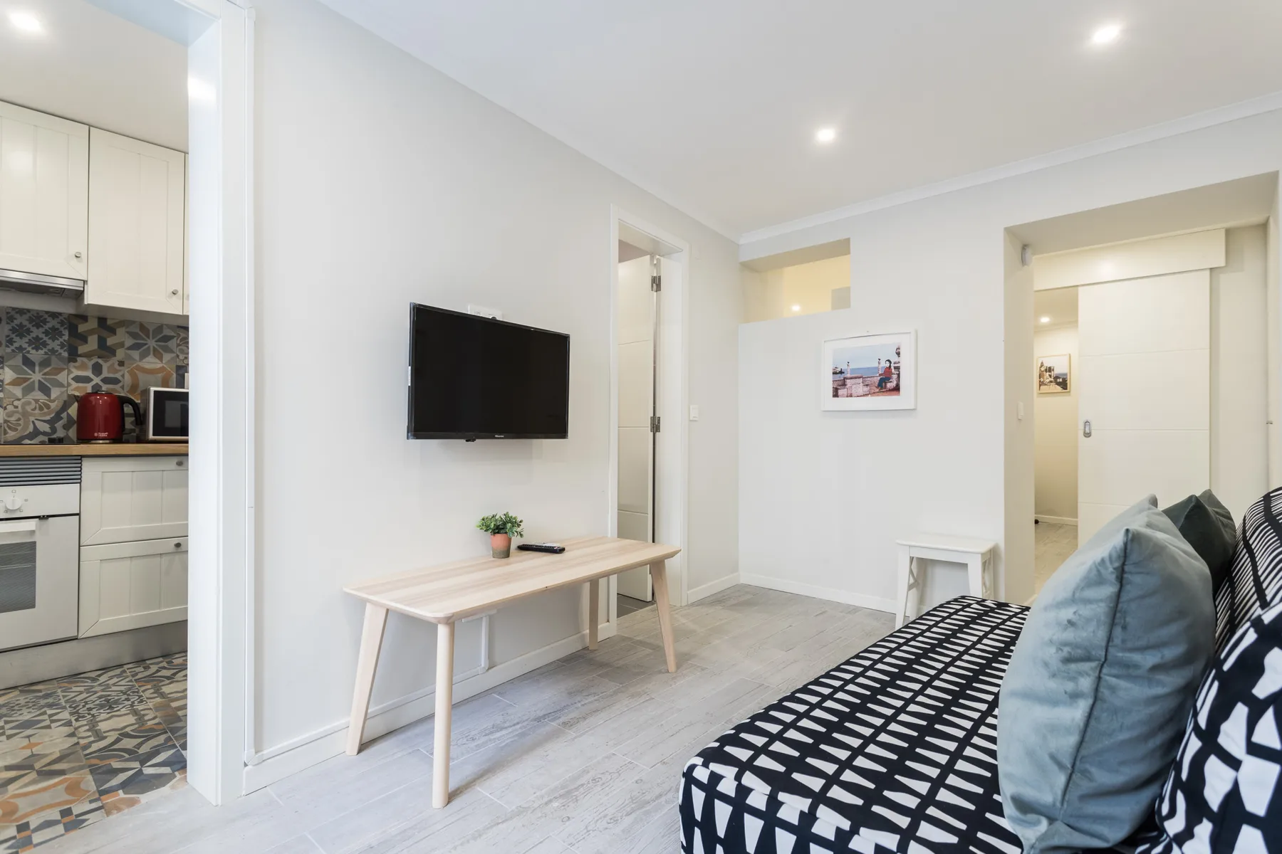 A bright living room with a television, small table, and patterned seating.