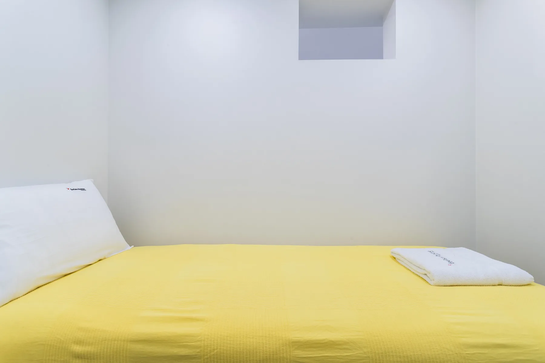 Un dormitorio con una colcha amarilla y almohadas blancas.