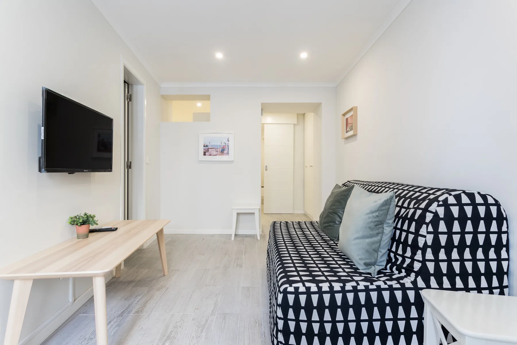 A bright living room with a patterned sofa and wall-mounted television.