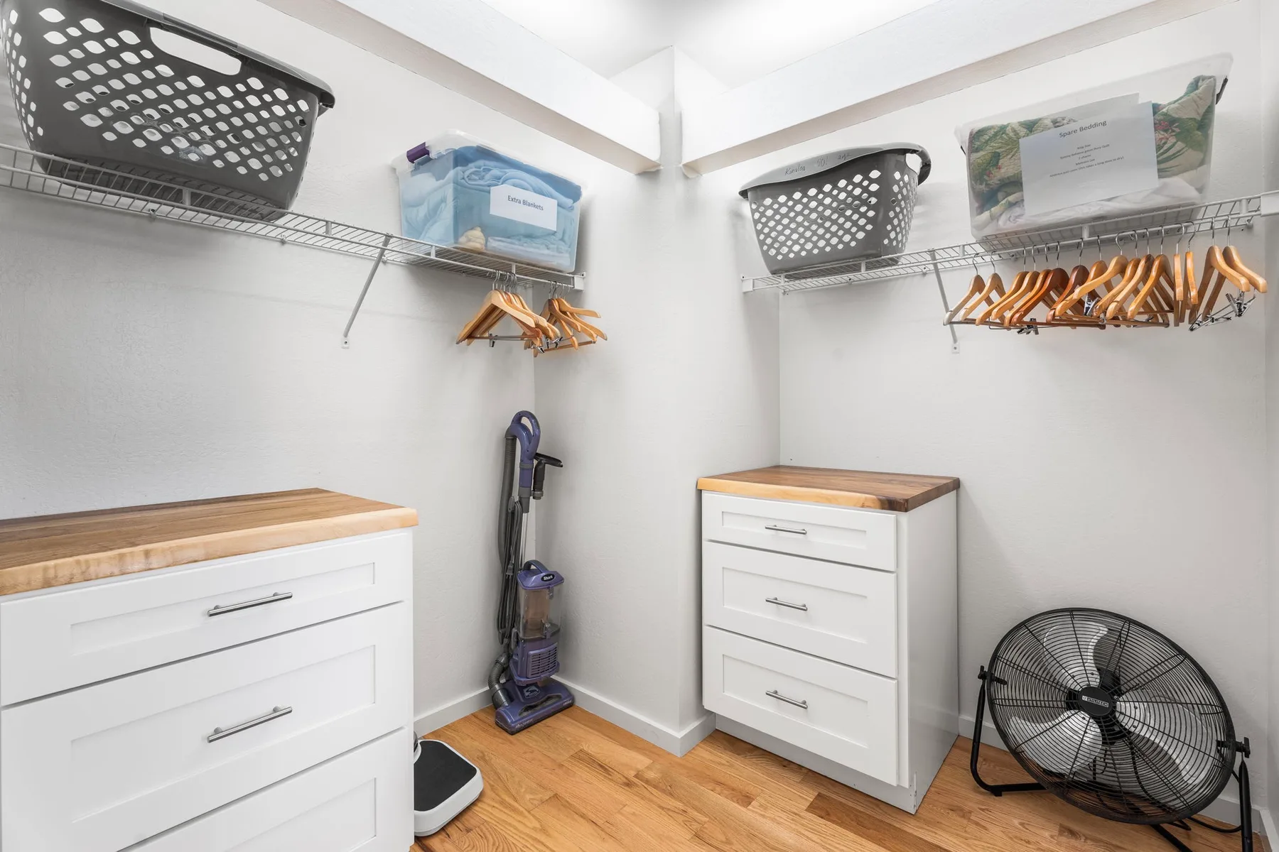 A walk-in closet with drawer units, hanging rods, and storage baskets.