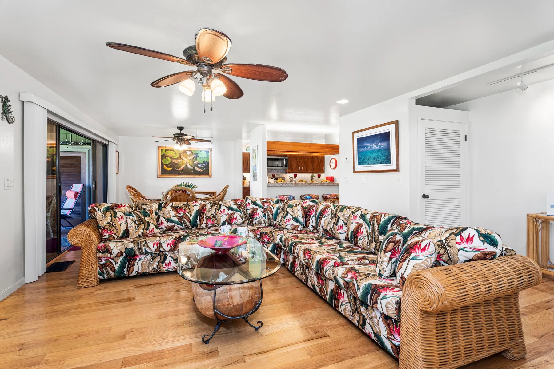 A living room with a patterned sectional and a glass coffee table.