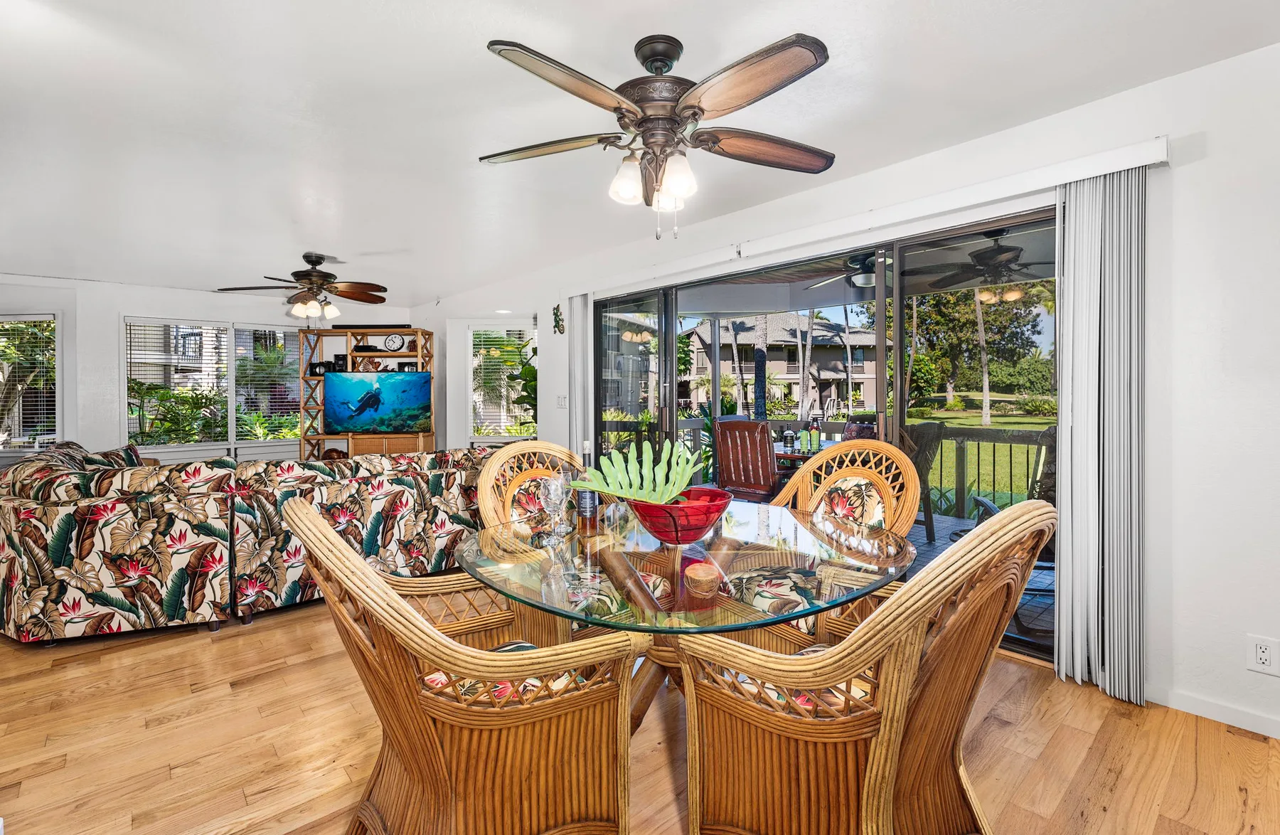 A bright living and dining area features wicker seating and a glass dining table.