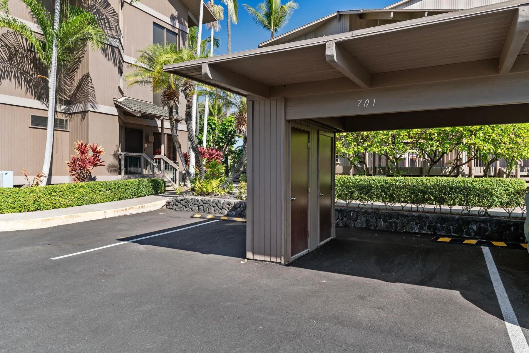 A covered parking area beside a landscaped building entrance.