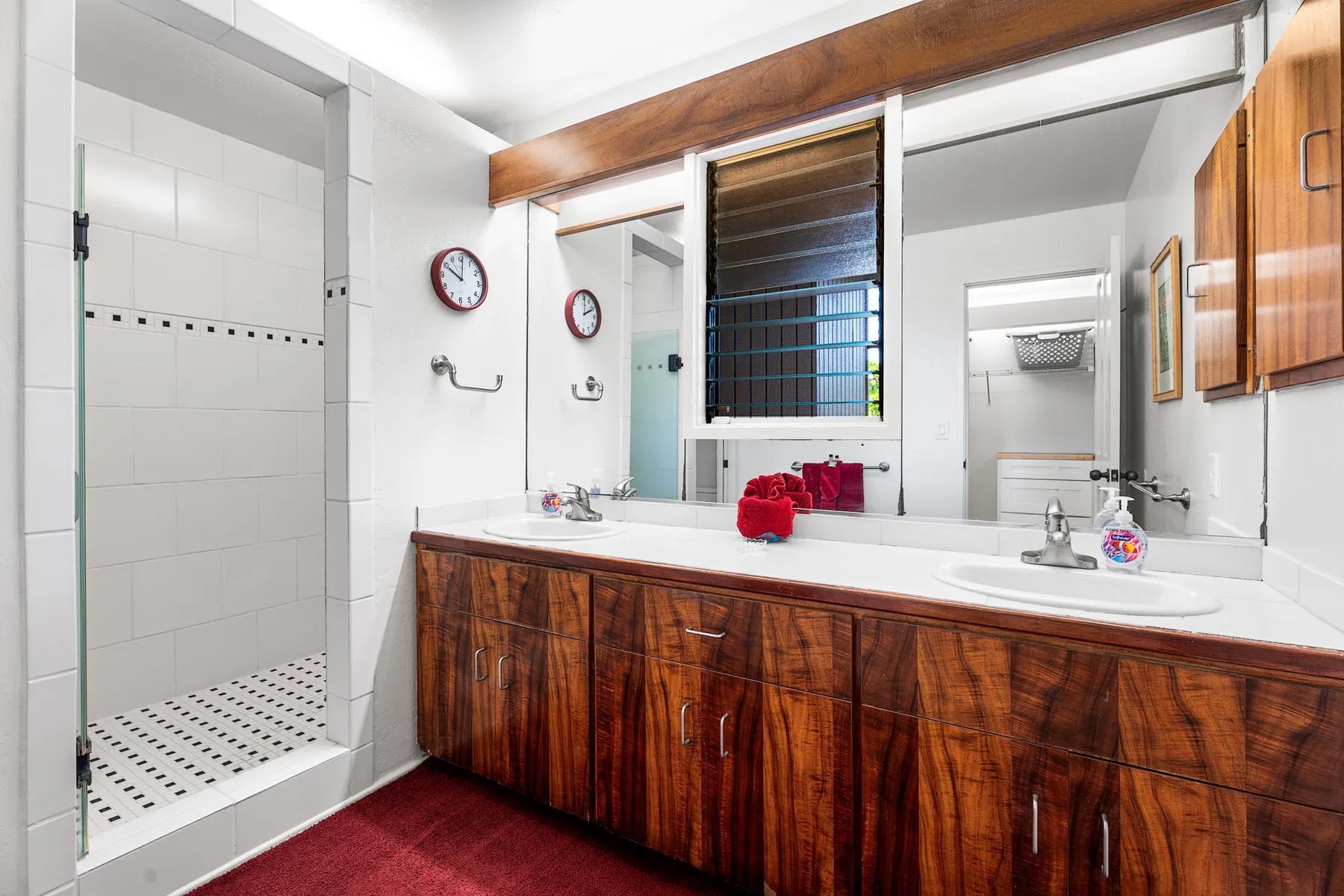 A bathroom with a long vanity, two sinks, and a walk-in shower.