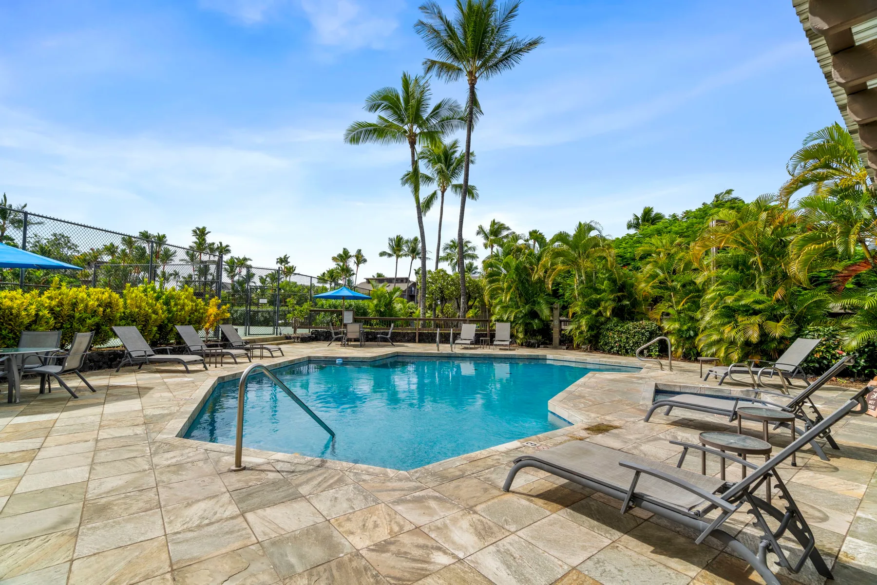 An outdoor swimming pool is surrounded by paved deck space and lounge seating.
