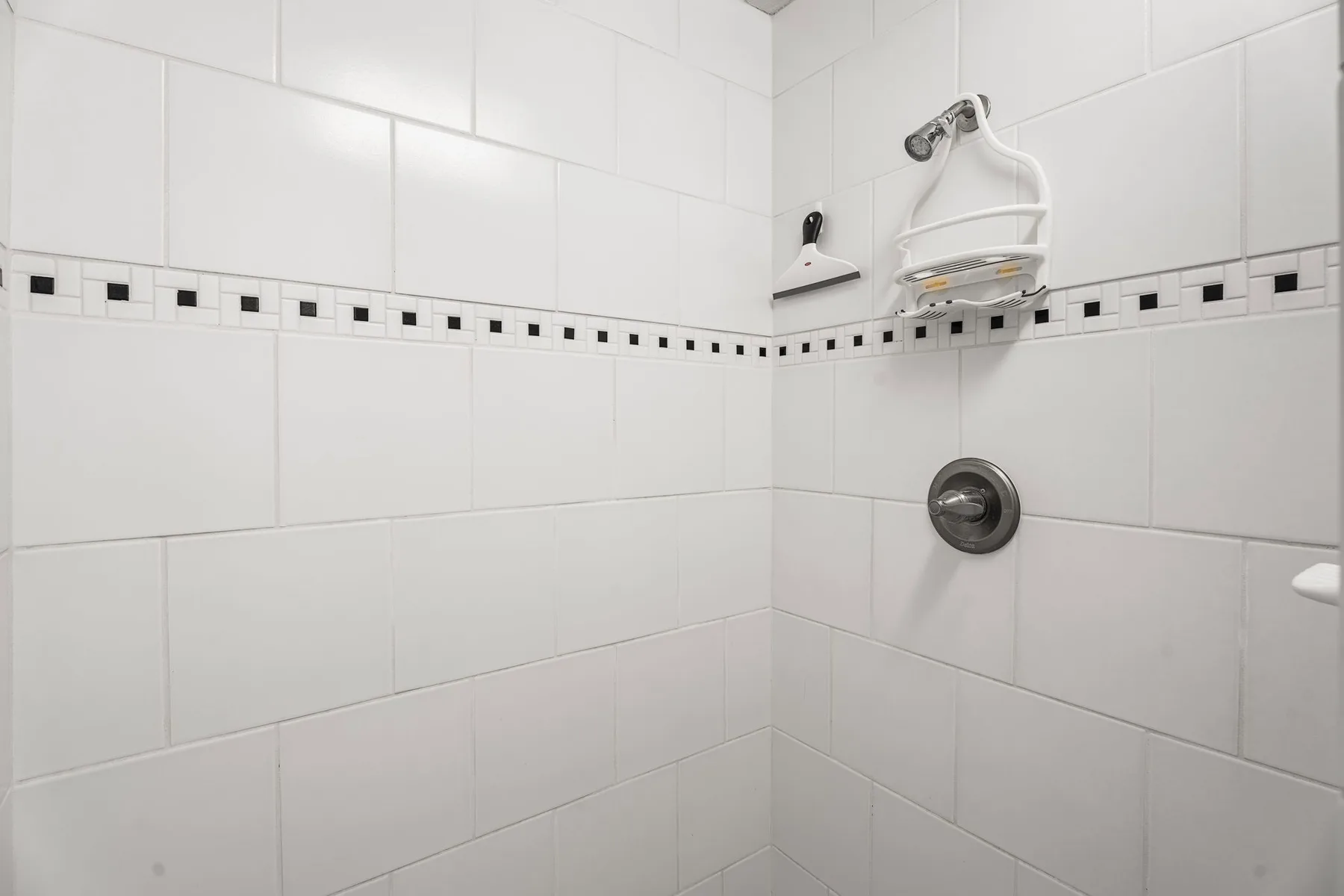 A tiled shower area with a wall-mounted showerhead and round control.