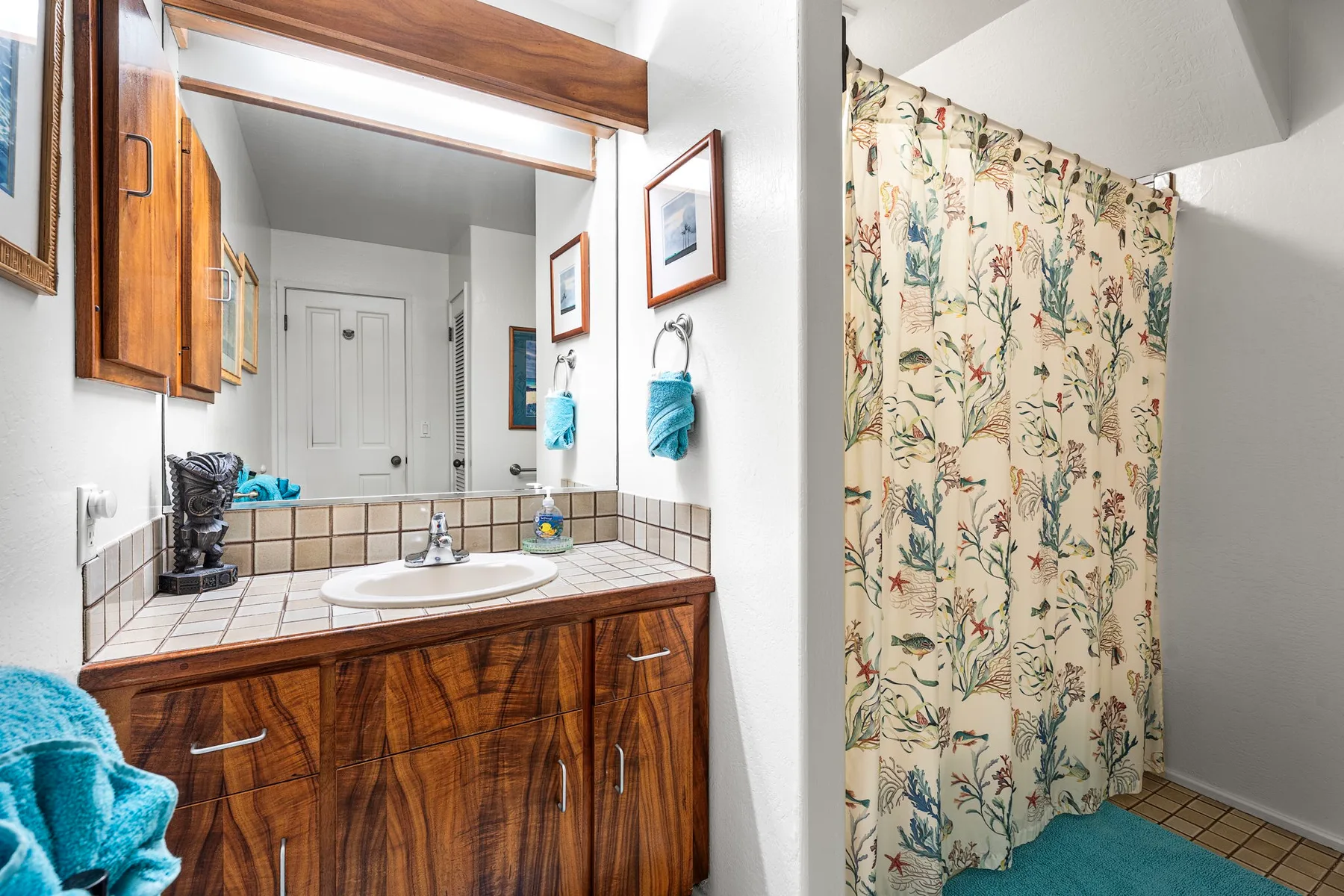 A bathroom vanity with a sink stands beside a patterned shower curtain.