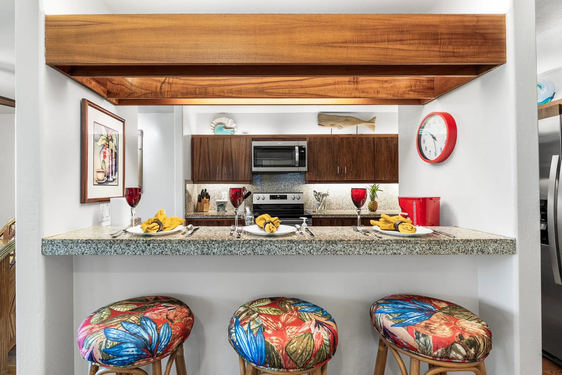 A kitchen with a breakfast bar and colorful stools beneath a wooden ceiling beam.