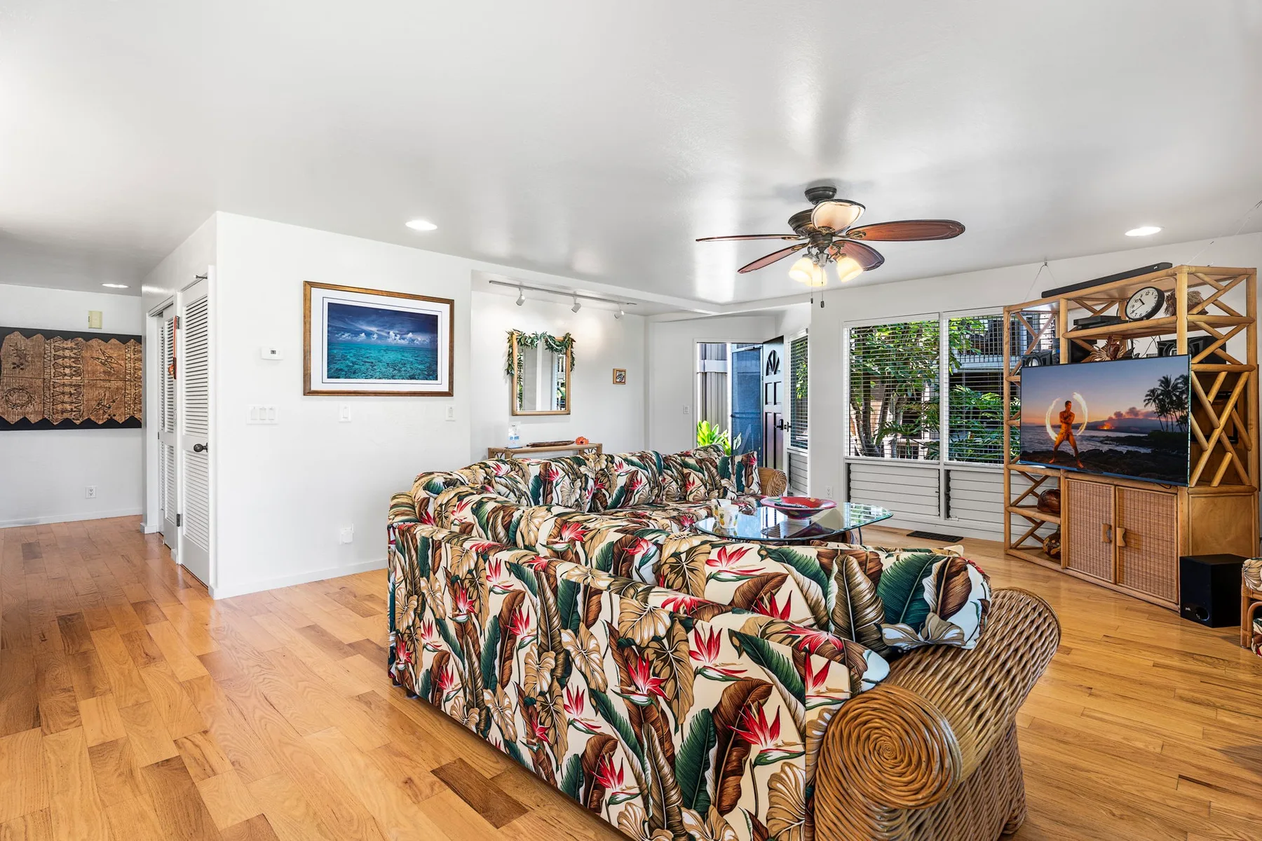 A living room with patterned seating and a television on a wooden stand.
