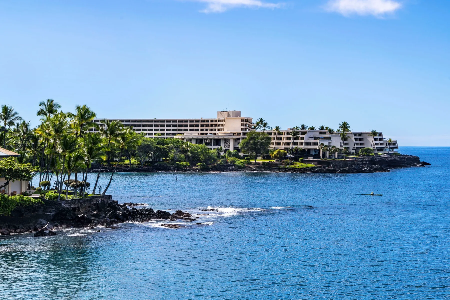 A coastal resort stretches along a rocky shoreline beside calm blue water.