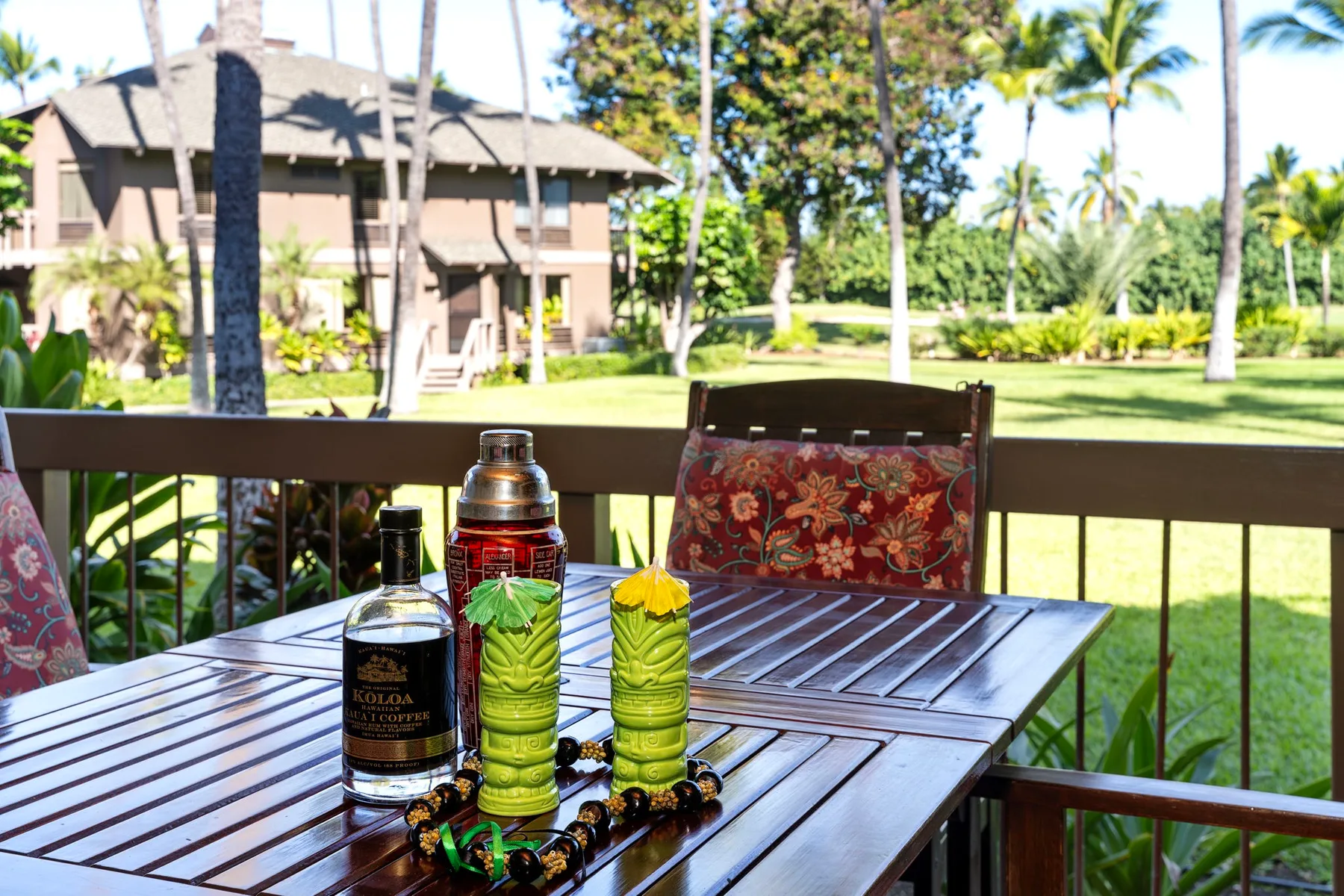 An outdoor patio table overlooks a garden and nearby buildings.