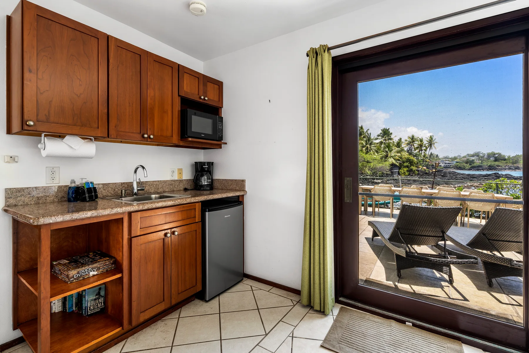 Una cocina compacta da a un balcón con asientos y vistas de palmeras.