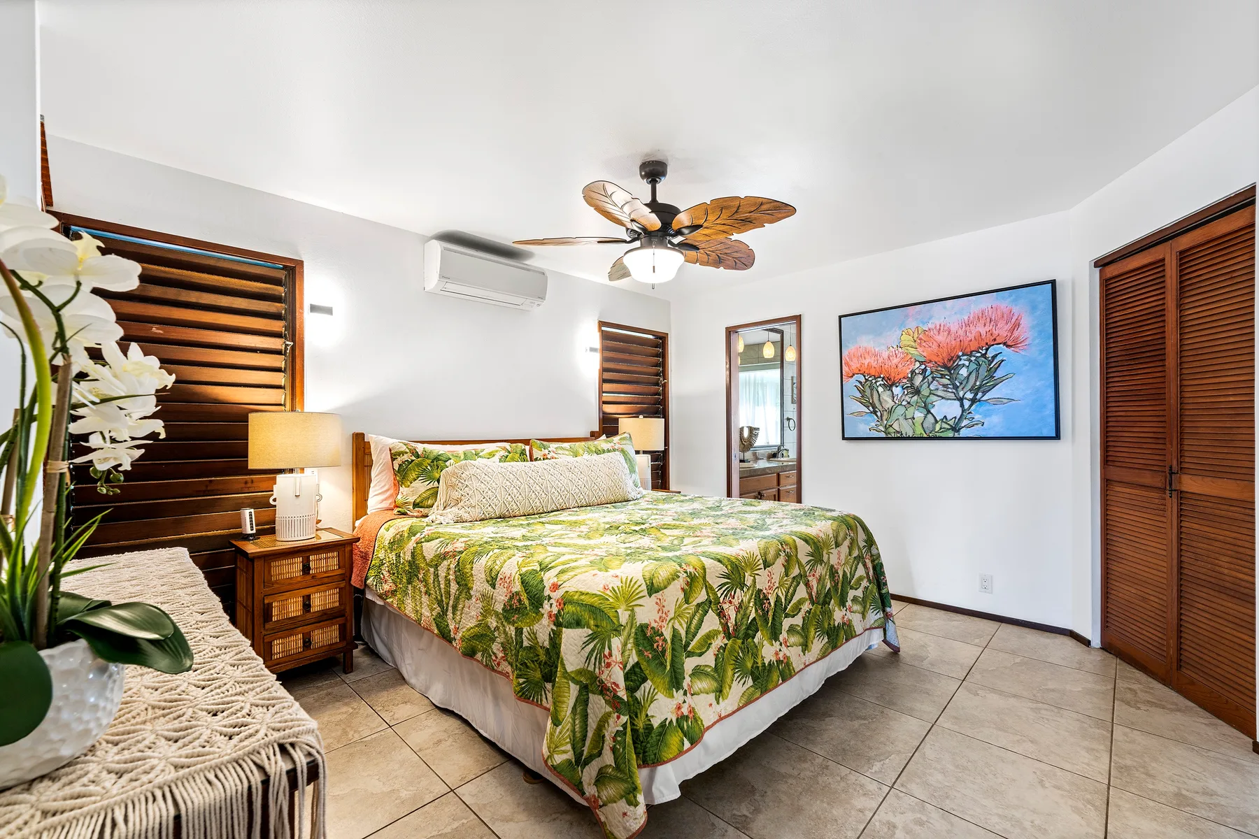 Un dormitorio con una cama cubierta con ropa de cama floral verde y arte enmarcado en la pared.