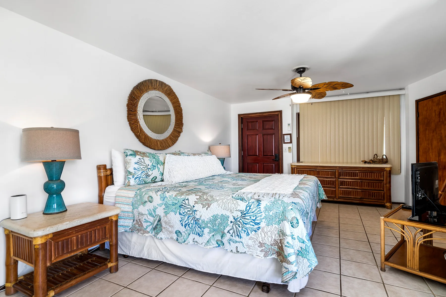 Un dormitorio con una cama cubierta con ropa de cama floral azul y muebles de madera.