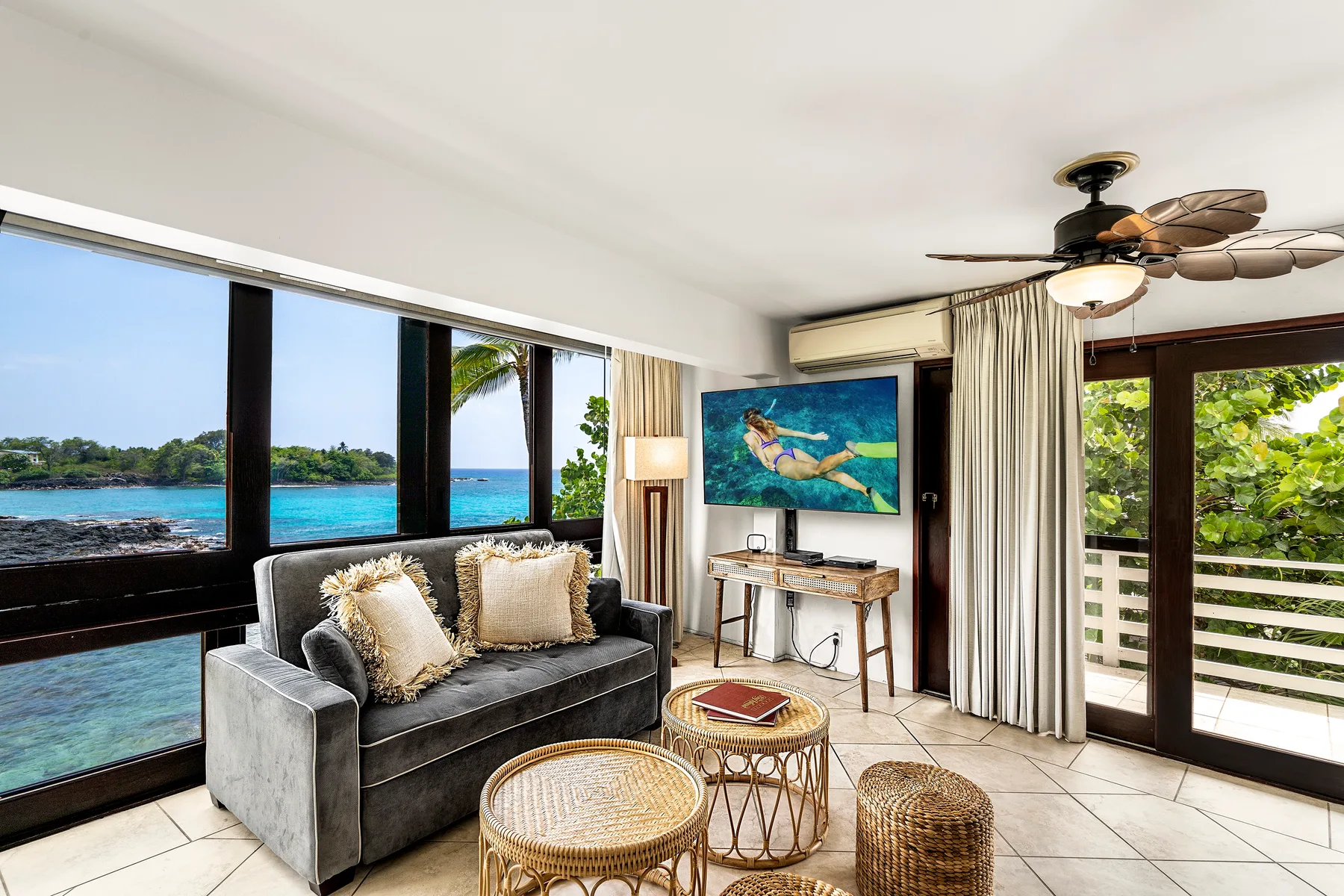 Una sala de estar con asientos junto a grandes ventanas con vista al agua.